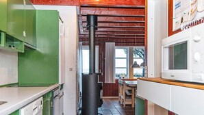 Een keuken met groene kastjes, een fornuis, een magnetron en een afvalbak.
