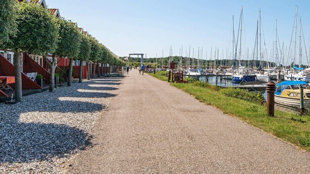 Een grindpad dat leidt naar een jachthaven met aangemeerde boten.