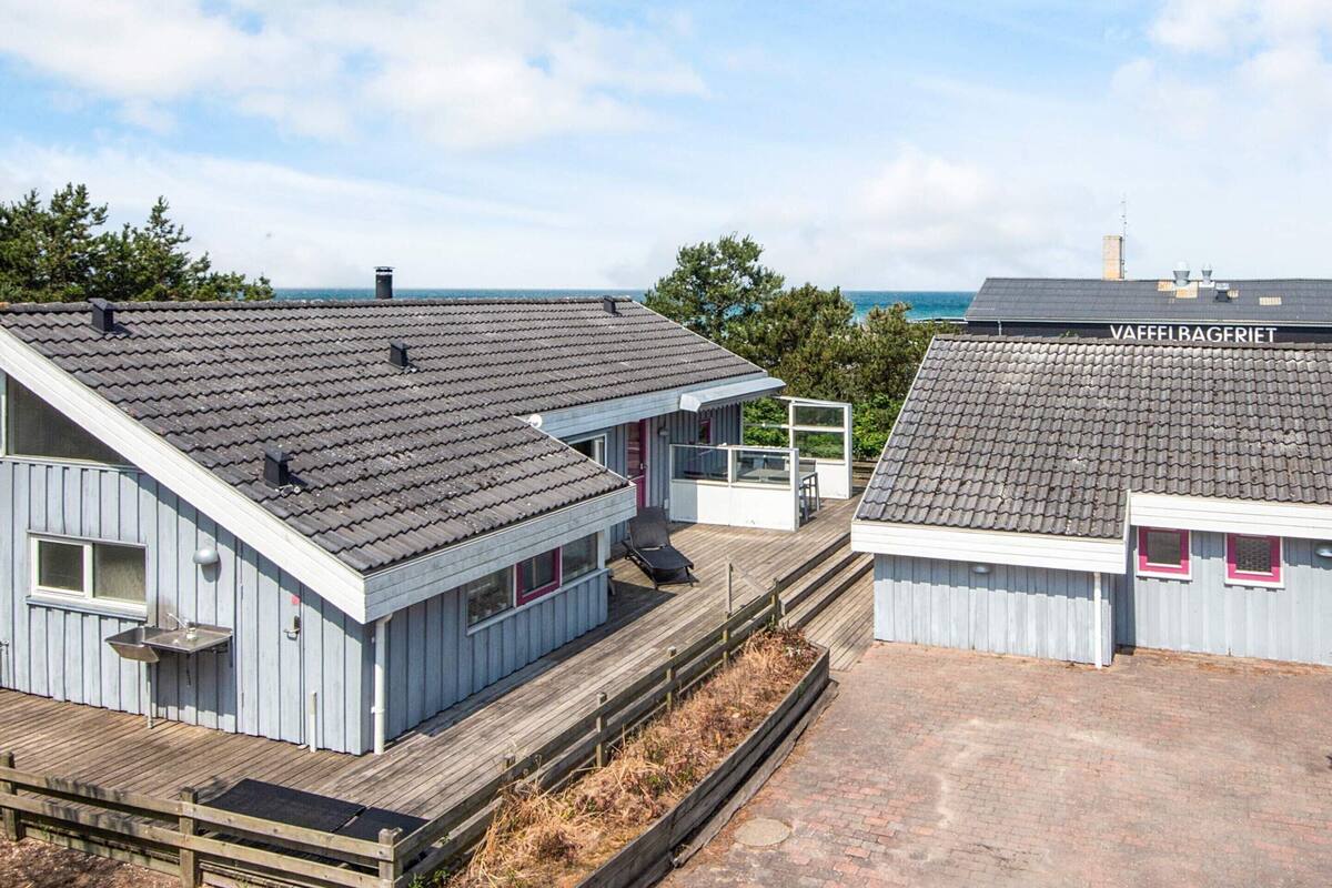 A coastal building with a sloped roof, a small deck, and a visible name sign.