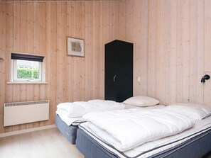 Un dormitorio con cama, ventana con vistas, armario negro y lámpara de pared.