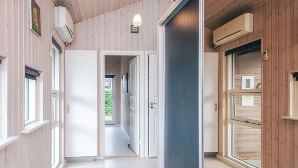 A corridor with wooden walls and a door leading to a room with a large window. - 5 Star Holiday Home in Ansager (Ansager)