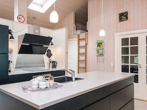 A modern kitchen with a large island, stainless steel appliances, and a wooden interior. - 5 Star Holiday Home in Ansager (Ansager)