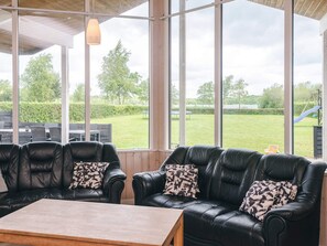 A room with a large window, a sofa set, and a wooden table.