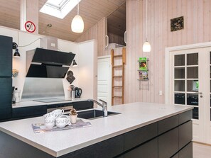A modern kitchen with a large island, stainless steel appliances, and a wooden interior.