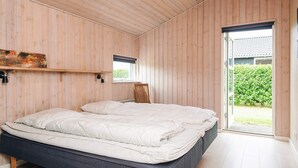 A bedroom with a double bed, wooden walls, a window, and a view of greenery outside. - 5 Star Holiday Home in Ansager (Ansager)