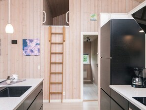 Une cuisine moderne avec des murs recouverts de panneaux en bois, une échelle intégrée et un réfrigérateur noir.
