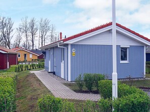 Un bâtiment bleu d’un seul étage, avec un toit rouge, un panneau indiquant le numéro de la rue et une petite fenêtre.