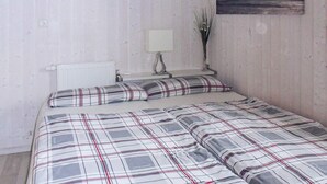 A bedroom with a bed, a nightstand, a lamp, and a painting on the wall. - Holiday Home in GrÃ¶mmitz (Groemitz)
