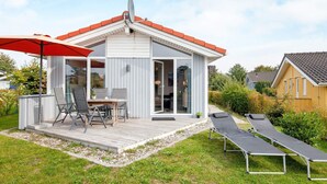 Ett modernt hus med en terrass, utemöbler och en satellitmottagare.