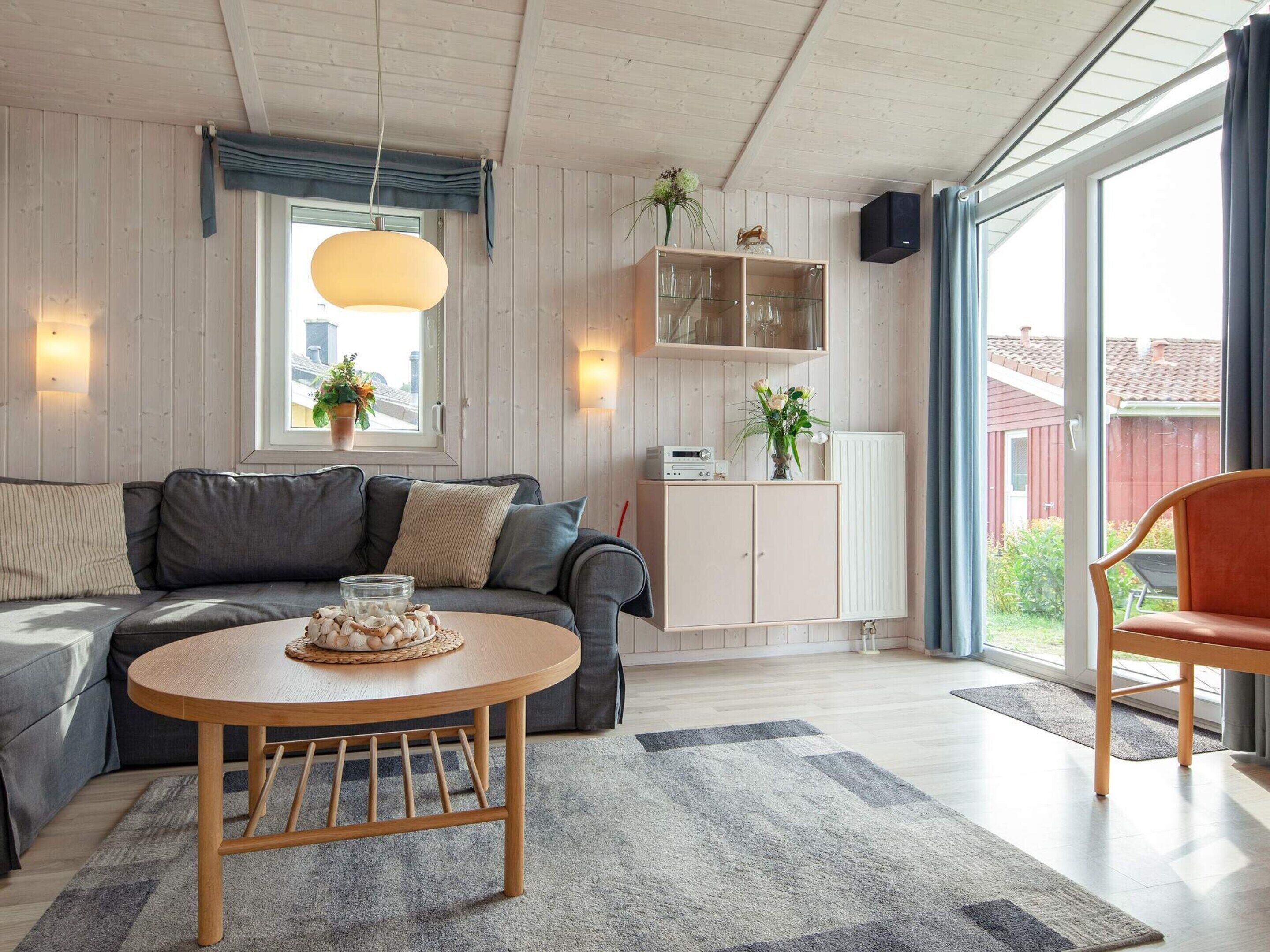 A modern living room with a grey sofa, a wooden coffee table, and a cabinet with glass doors.