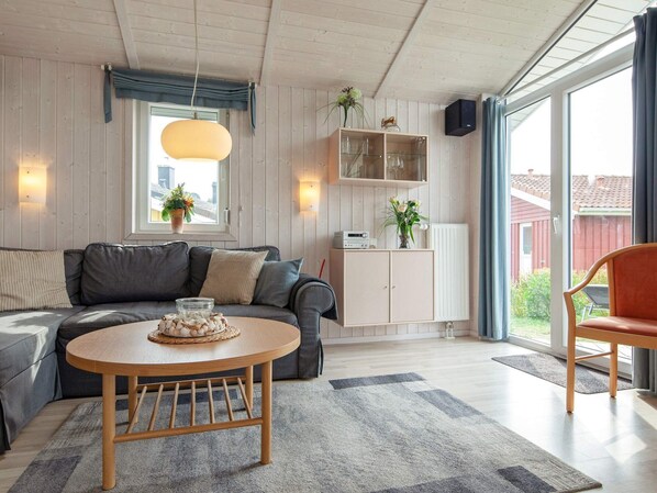 Un salon moderne avec un canapé gris, une table basse en bois et un meuble avec des portes en verre.