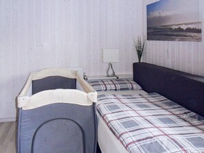 A room with two beds, a nightstand, a lamp, and a wall-mounted painting. - Holiday Home in GrÃ¶mmitz (Groemitz)