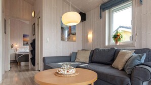 A cozy living room with a grey sofa, a round wooden coffee table, and a painting on the wall. - Holiday Home in GrÃ¶mmitz (Groemitz)