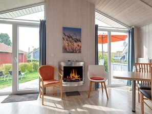 A modern living room with a fireplace, two chairs, a table, and a view of the outdoors. - Holiday Home in GrÃ¶mmitz (Groemitz)