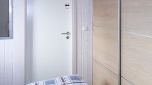 A white door with a keyhole and a handle, a small window, and a wall with a wooden panel design. - Holiday Home in GrÃ¶mmitz (Groemitz)