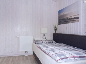 Une chambre à coucher avec un lit, un radiateur, une table de chevet avec une lampe et un tableau accroché au mur.