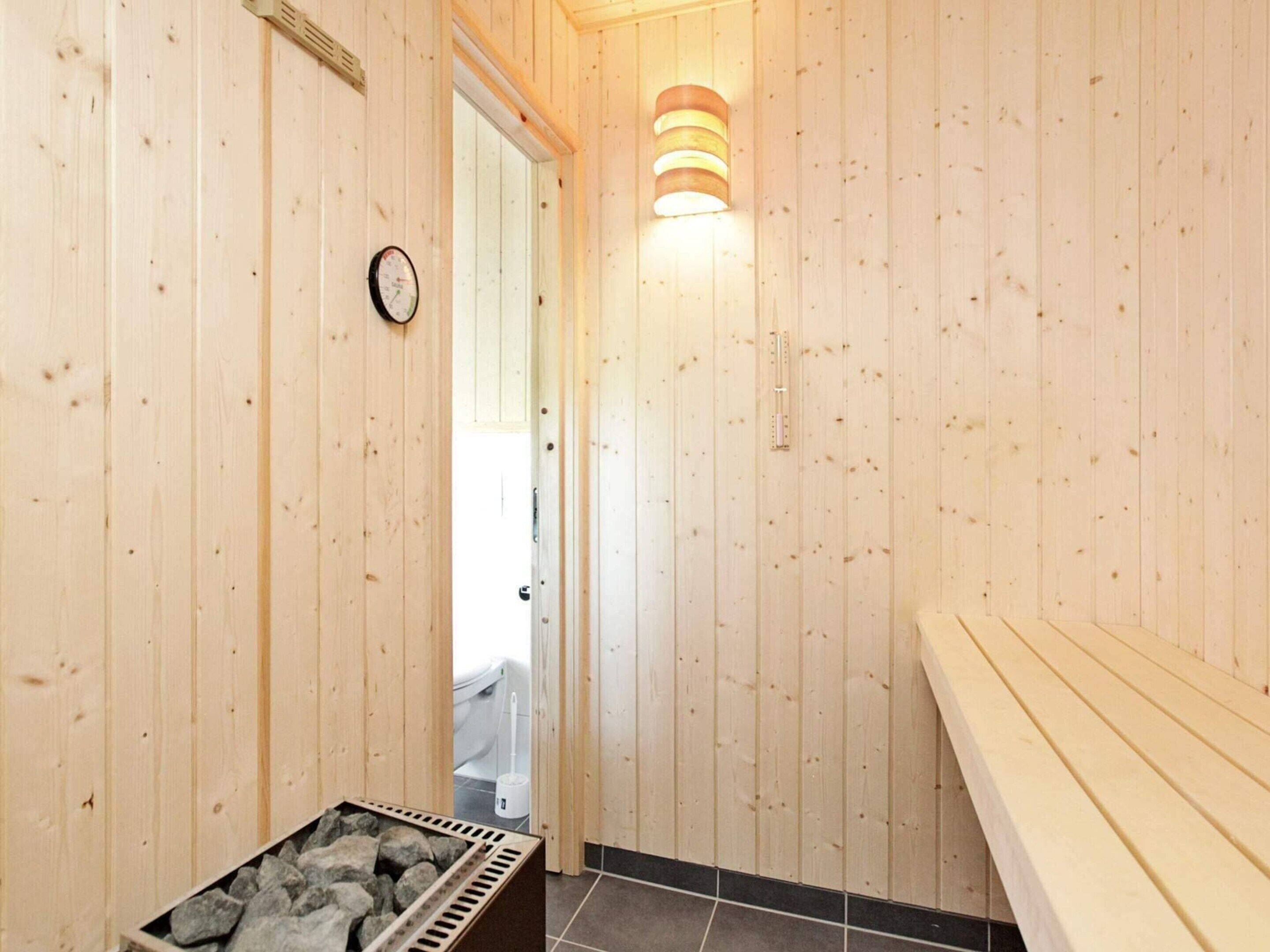 Ein Holzinnenraum mit Sauna, einer Uhr und einer Wandleuchte.