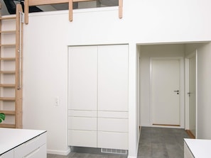 A room with a white wardrobe, a wooden ladder, and a door leading to another room. - 5 Star Holiday Home in Ringkobing (Ringkobing)