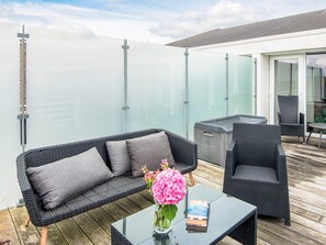 Ein Balkon mit Korbmöbeln, einem Glastisch und einem Buch.