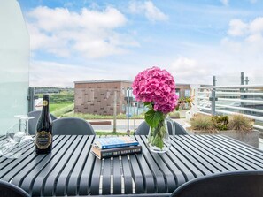 Une table avec une bouteille, un livre et un vase de fleurs.