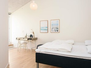 A bedroom with a bed, a desk with a chair, and two framed pictures on the wall. - 5 Star Holiday Home in Ringkobing (Ringkobing)