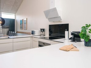 Une cuisine moderne équipée d’une cuisinière intégrée, d’une machine à café et d’un évier.