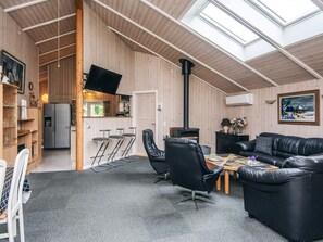 A cozy interior with a high ceiling, a fireplace, a dining area, and a seating area with a couch and chairs. - 4 Star Holiday Home in Ansager (Ansager)