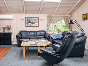 Uma sala de estar acolhedora com um sofá de couro preto, uma mesa de centro de madeira e uma poltrona preta.