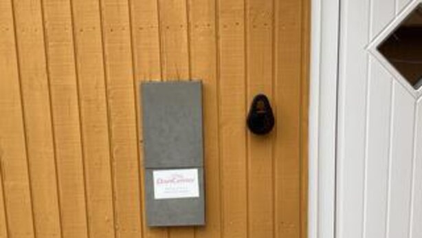 A wooden door with a gray intercom box and a black doorbell. - Lakeview Retreat With Spa (Ansager)