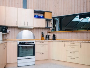 Une cuisine compacte avec des meubles en bois, un four encastré et une fenêtre donnant sur le ciel.