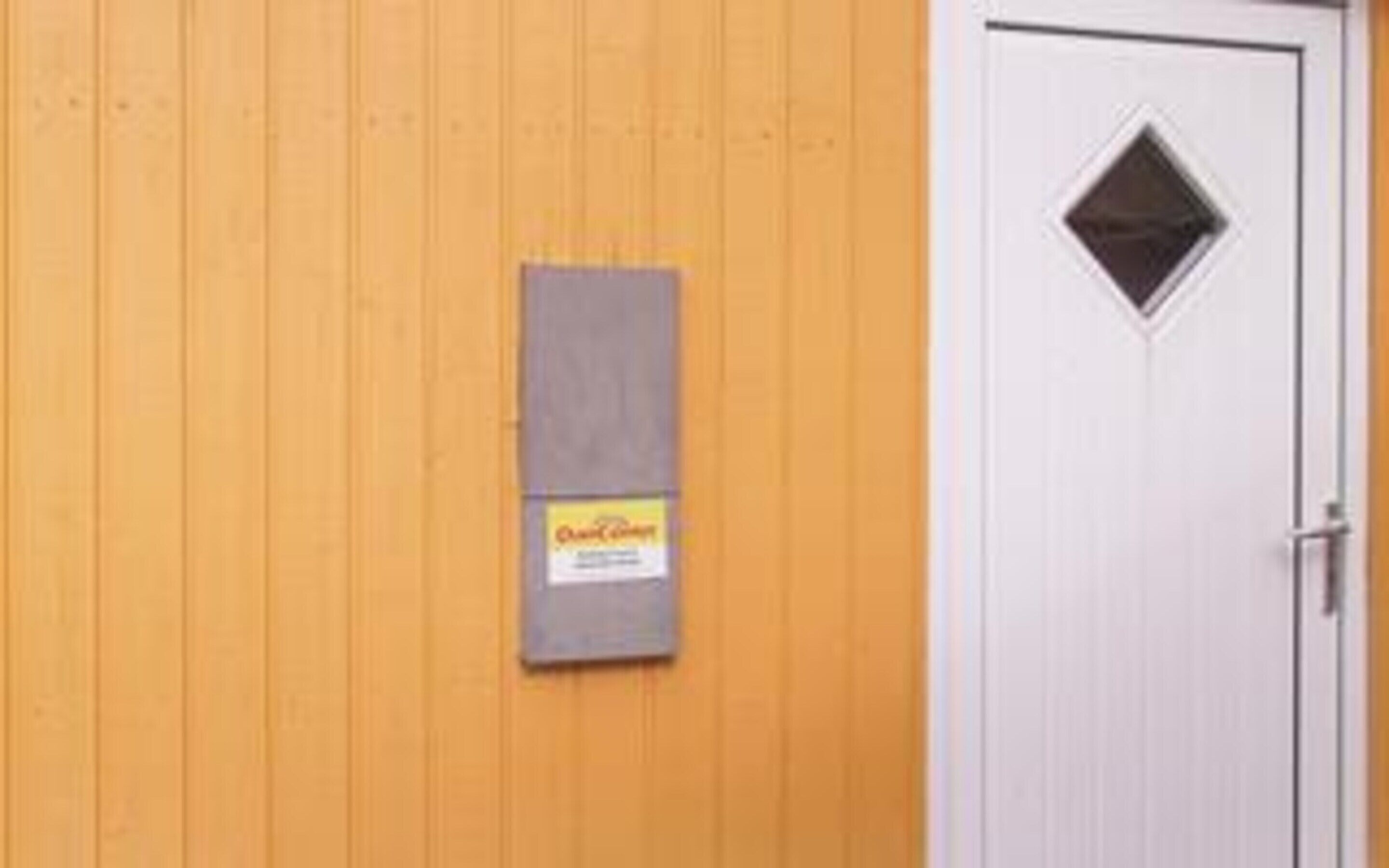 A wooden wall with a door and a mailbox.