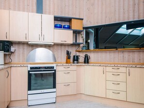 A compact kitchen with wooden cabinets, a built-in oven, and a window above the sink. - 4 Star Holiday Home in Ansager (Ansager)