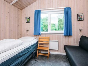 A room with a bed, a bench, a radiator, and a window with curtains. - 4 Star Holiday Home in Ansager (Ansager)