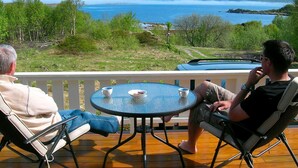 A balcony with two chairs and a round table, overlooking a mountainous landscape and a body of water. - Holiday Home in Leknes (Vestvågøy)
