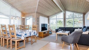 A spacious living area with a dining table, sofas, and a television.
