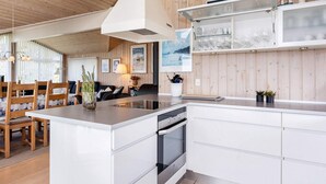 A modern kitchen with white cabinetry, a central island, and a built-in oven. - 4 Star Holiday Home in Hjorring (Hjørring)