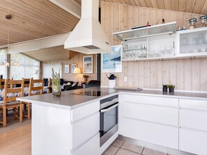 Une cuisine moderne avec des meubles blancs, un îlot central et un four encastré.