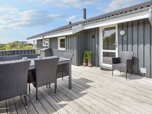 A wooden deck with outdoor furniture, a covered patio area, and a building with a grey facade. - 4 Star Holiday Home in Hjorring (Hjørring)