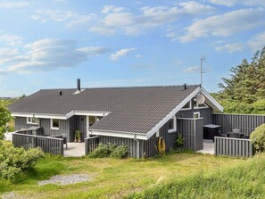 A modern house with a sloped roof, a satellite dish, and a fenced yard.