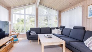 A modern living room with a sectional sofa, a wooden coffee table, and a television.