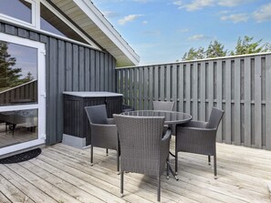 A deck with a round table and four chairs, a sliding glass door, and a wooden fence. - 4 Star Holiday Home in Hjorring (Hjørring)