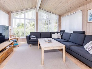 A modern living room with a sectional sofa, a wooden coffee table, and a television on a wooden stand. - 4 Star Holiday Home in Hjorring (Hjørring)