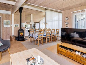 A cozy living room with a fireplace, dining area, and a TV on a wooden stand.