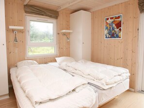 A bedroom with a bed, two bedside lamps, a window, and a painting on the wall. - 4 Star Holiday Home in Hjorring (Hjørring)