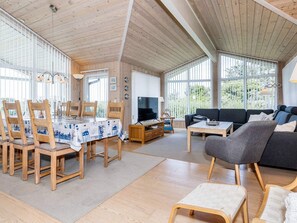 A spacious living area with a dining table, chairs, a sofa, and a television. - 4 Star Holiday Home in Hjorring (Hjørring)