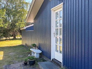 A blue building with a white door and windows, a small bench, and potted plants. - 6 Person Holiday Home in Rodby-by Traum (Rodby)