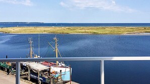 Eine Küstenansicht mit einem an einem Steg vertäuten Schiff, einem kleinen Boot und einer fernen Küstenlinie.