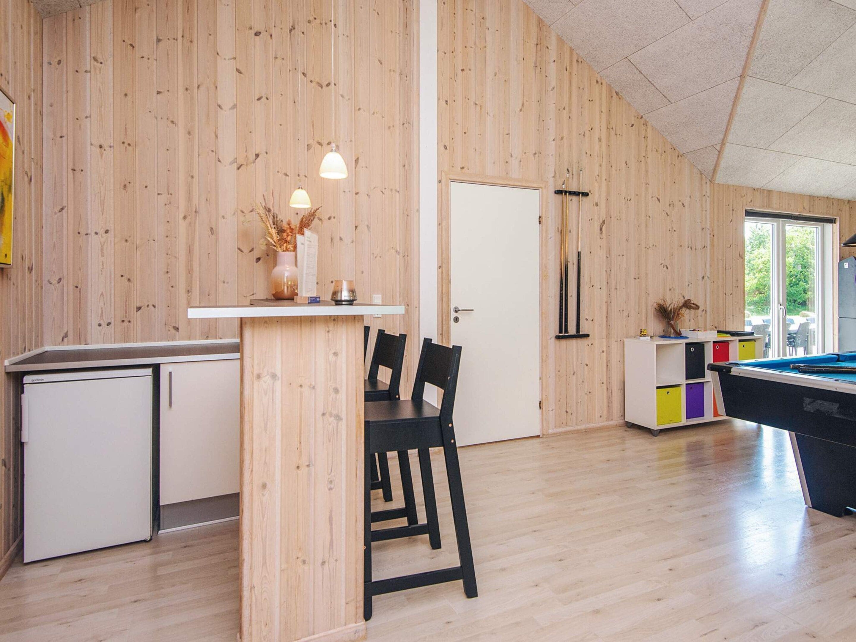 Ein modernes Interieur mit Holzwänden, einem Billardtisch, einer kleinen Bar und einem Essbereich.
