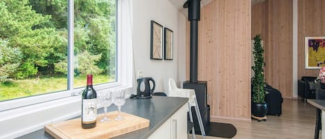 A modern kitchen with a large window, a wine bottle, and glasses on the counter.