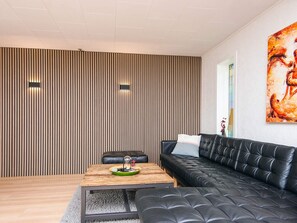 A modern living room with a sectional sofa, a wooden coffee table, and a wall with vertical slats. - 4 Star Holiday Home in Ulfborg (Ulfborg)